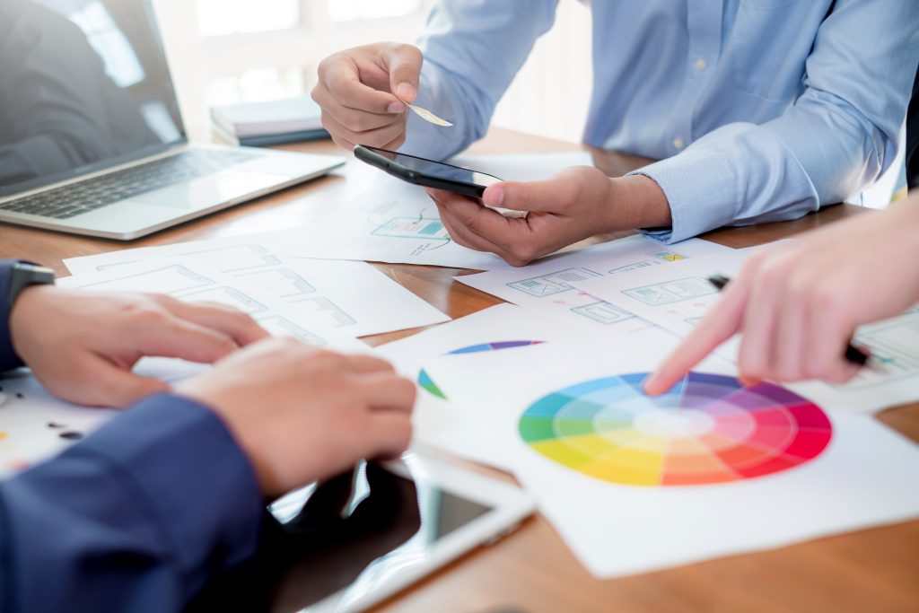UI UX Graphic designer. Group of designer creativity drawing a website outline and website ux app development on mobile phone.
